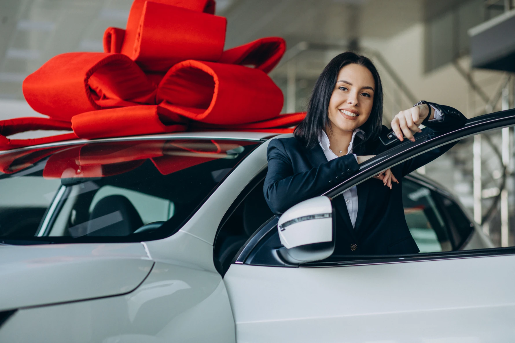 Mulher ao lado de um carro novo decorado com um grande laço vermelho